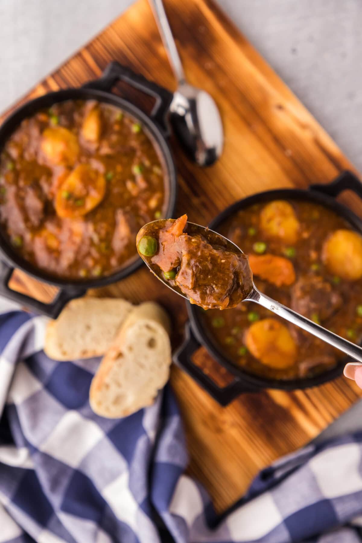 Spoonful of Instant Pot Beef Stew above two bowls of Instant Pot Beef Stew