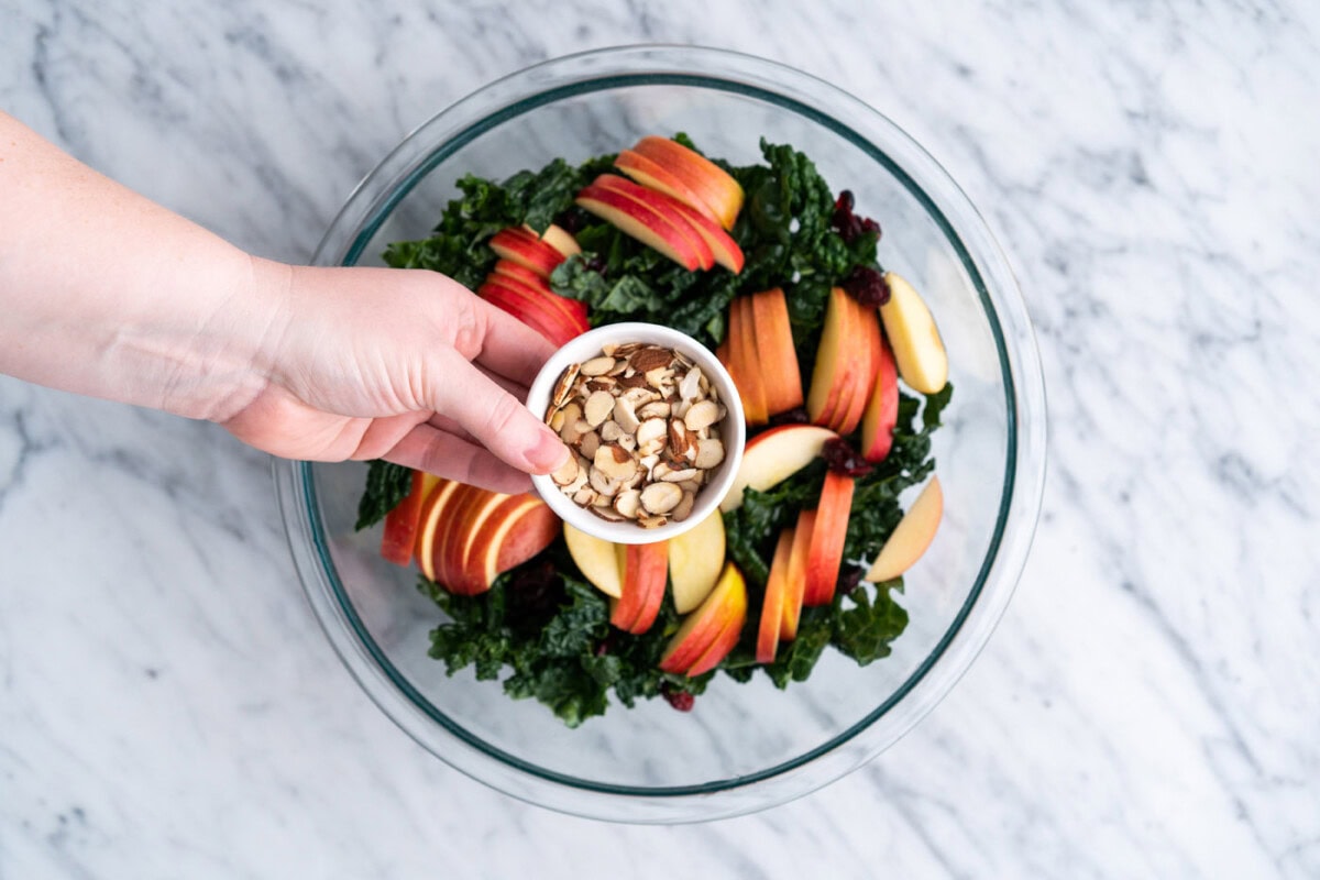 adding almonds to kale salad