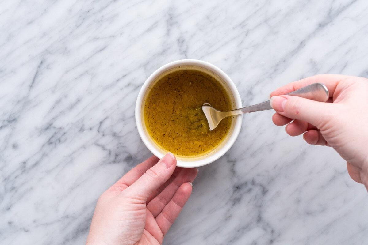 whisking lemon dressing in a small bowl with a fork