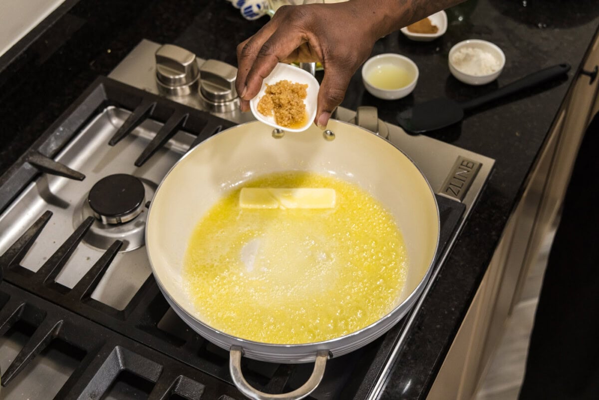 adding minced garlic to butter in a skillet