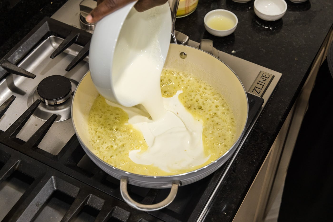 pouring heavy cream into skillet with garlic butter mixture