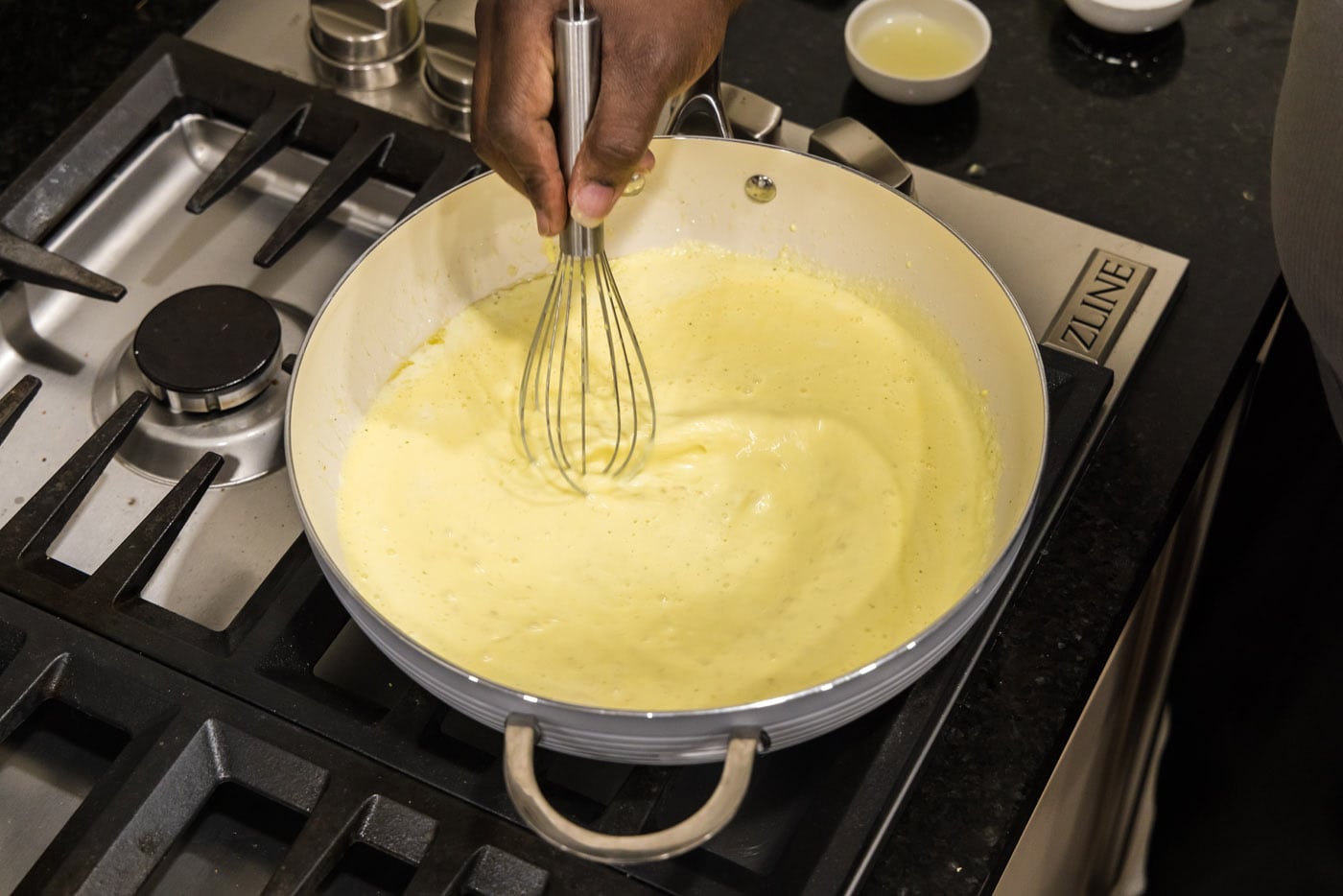 whisking egg mixture into cream in a hot skillet