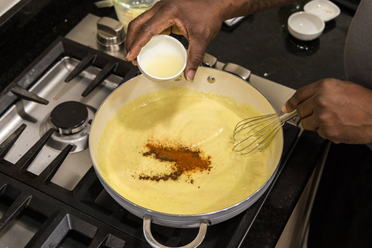 adding lemon juice to cream mixture with seasonings in a skillet