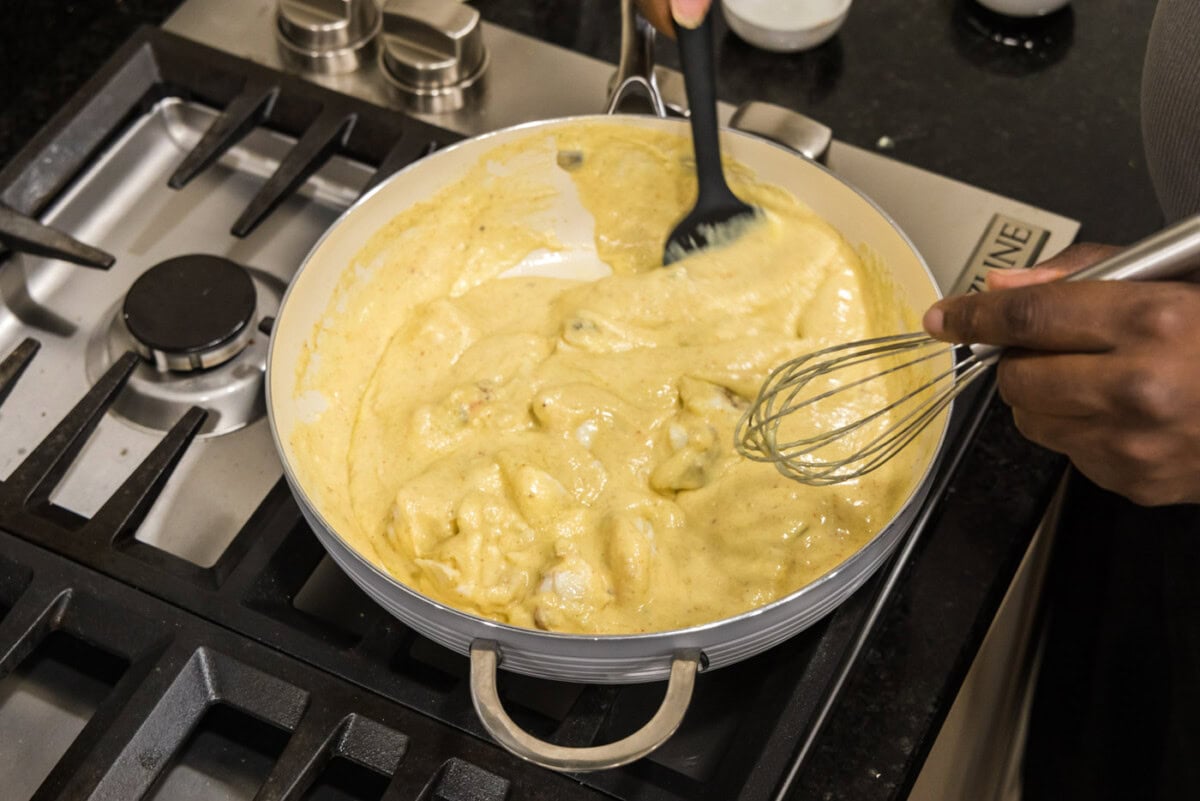 mixing lobster chunks into cream sauce for lobster newburg