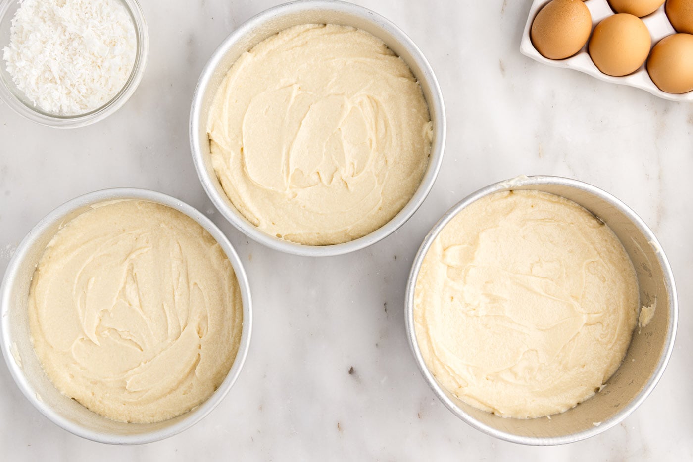 coconut cake batter in round cake pans