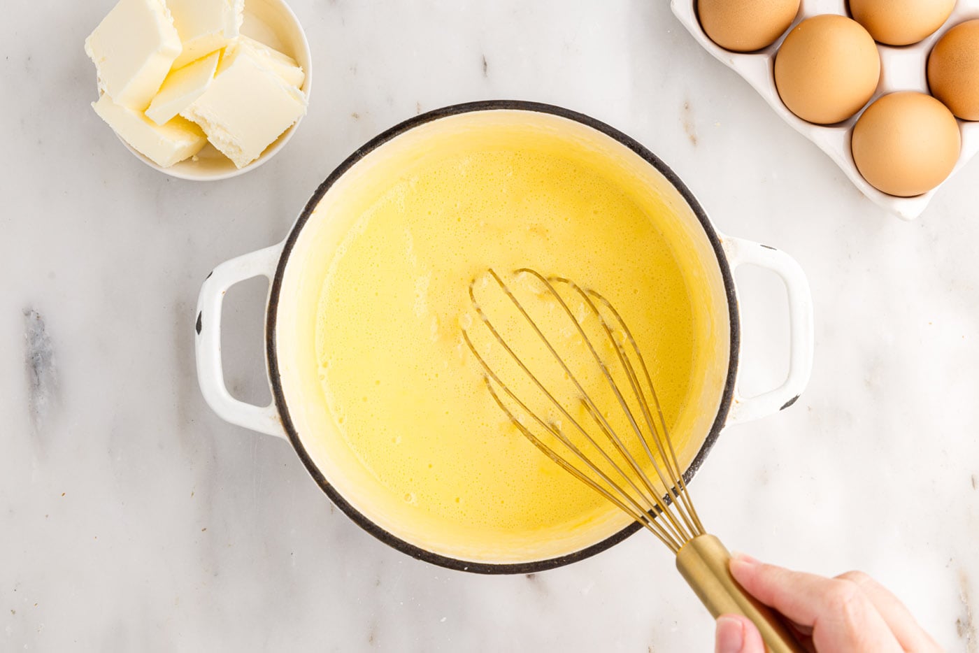 whisking pineapple curd in a saucepan