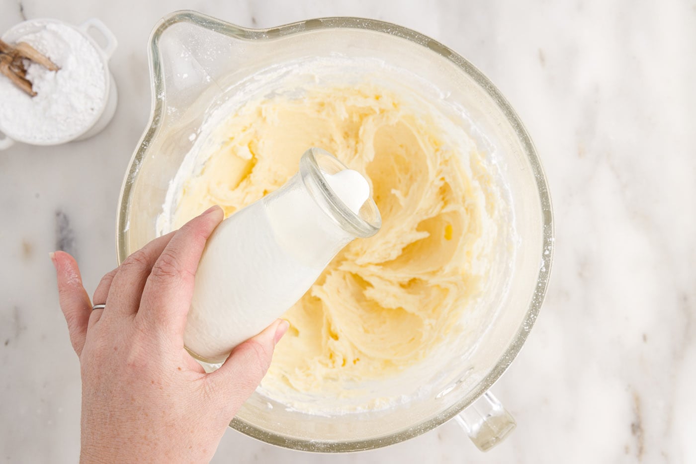 pouring heavy cream into cream cheese frosting