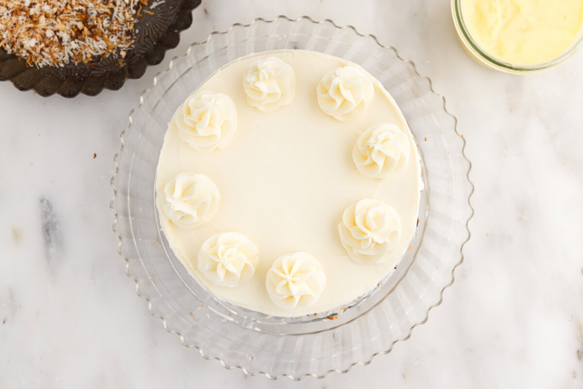 piped cream cheese frosting on top of frosted cake
