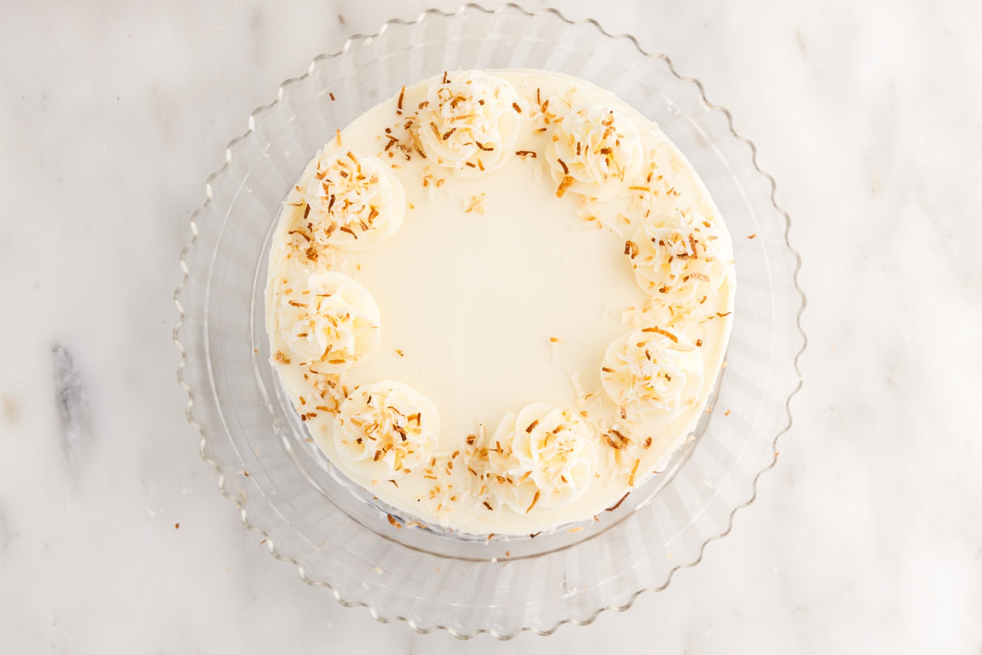 toasted coconut added on top of frosted pineapple coconut cake