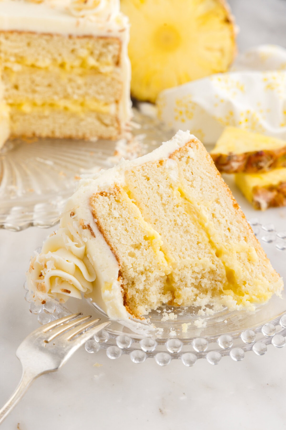 Partially eaten slice of Pineapple Coconut Cake on a plate with a fork