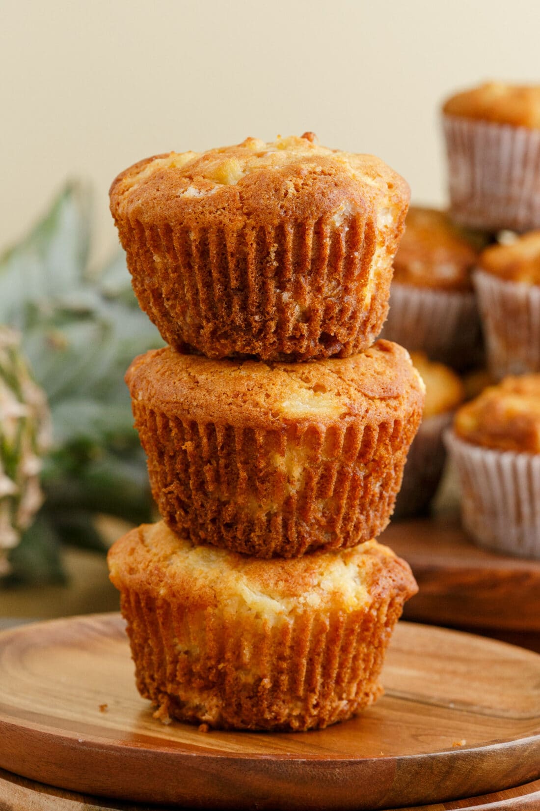 Stack of three Pineapple Muffins on a wooden plate