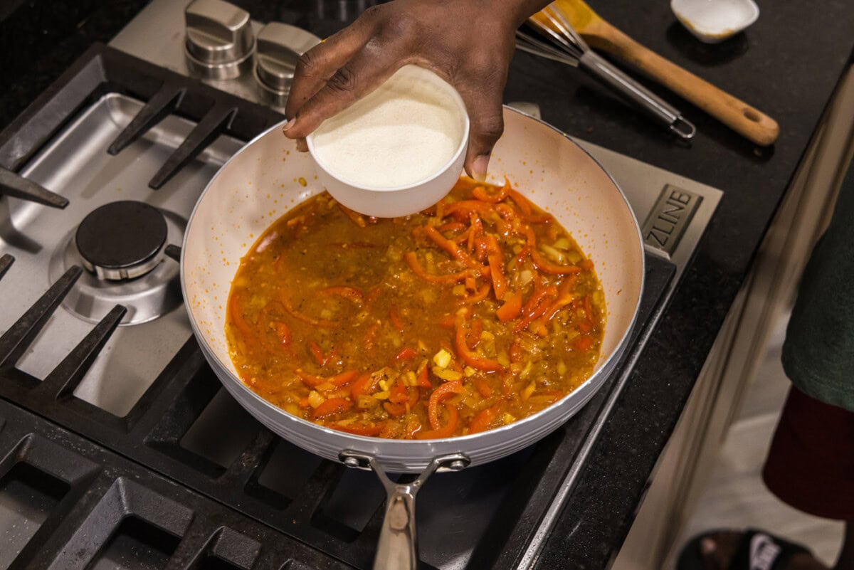 adding heavy cream to skillet with curry gravy