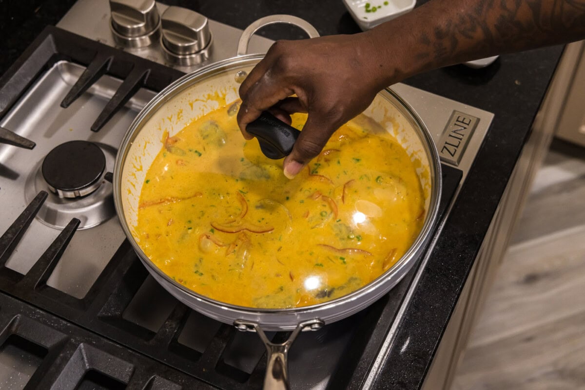 placing a lid on shrimp curry on the stovetop