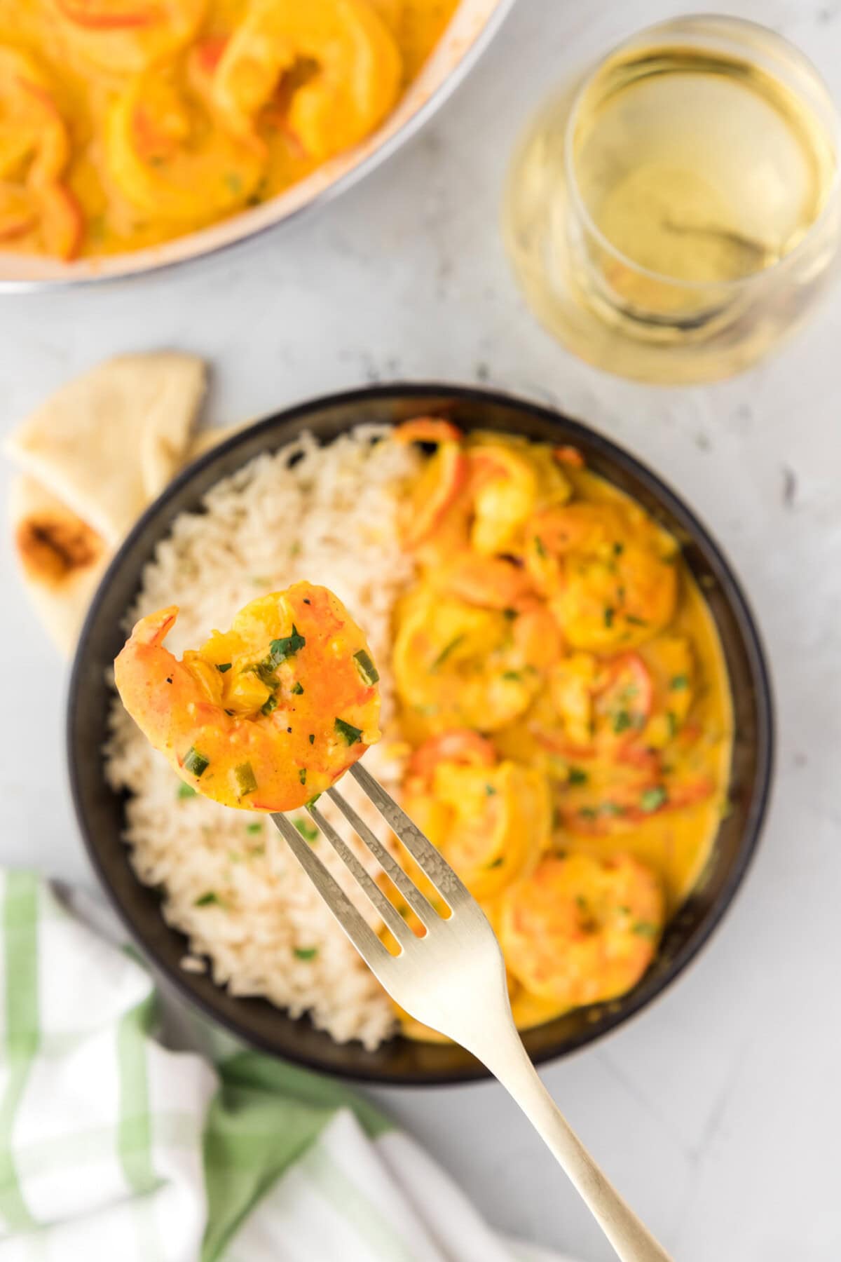 Shrimp Curry on a fork held above a bowl of Shrimp Curry with rice