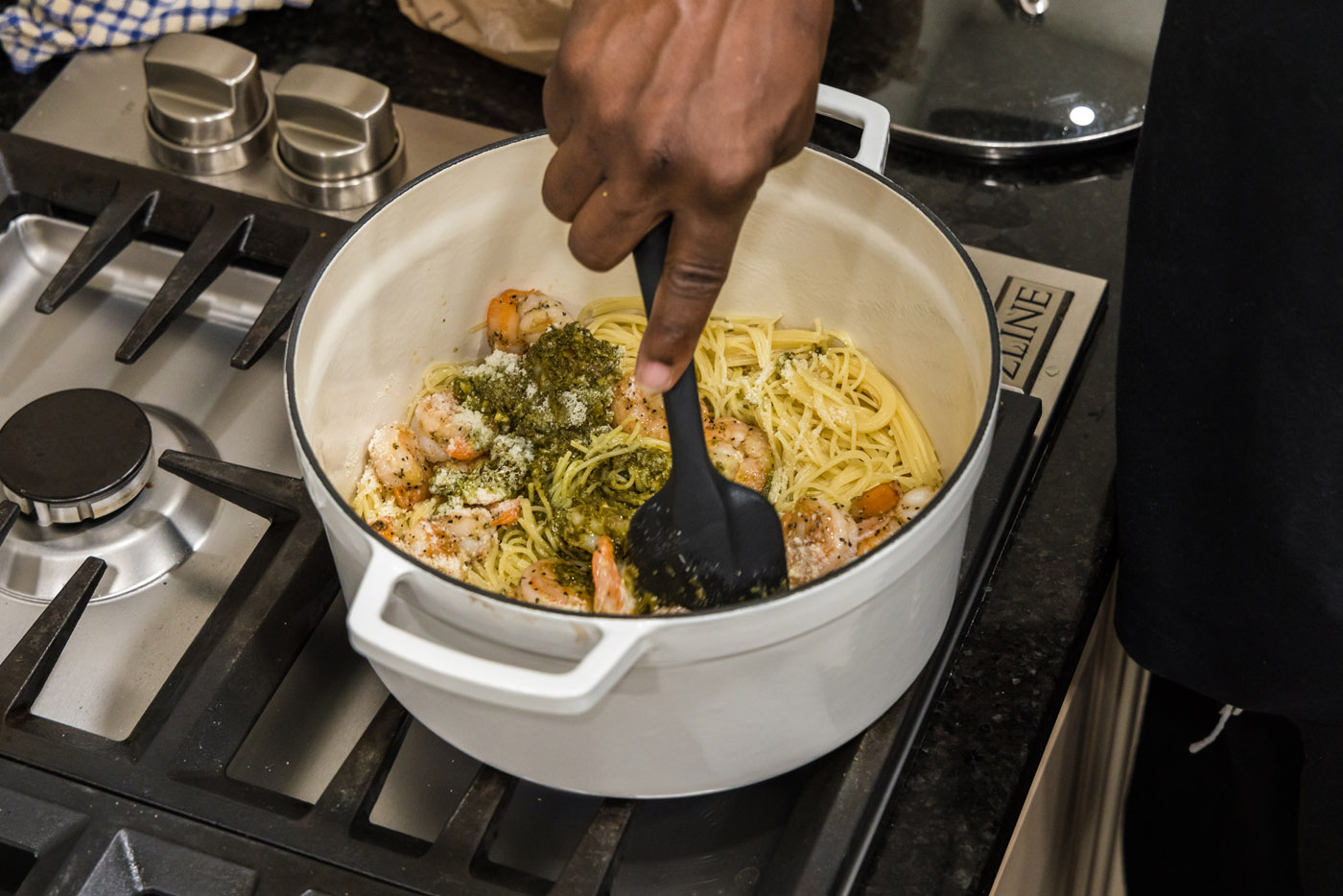 stirring shrimp pesto pasta with a rubber spatula