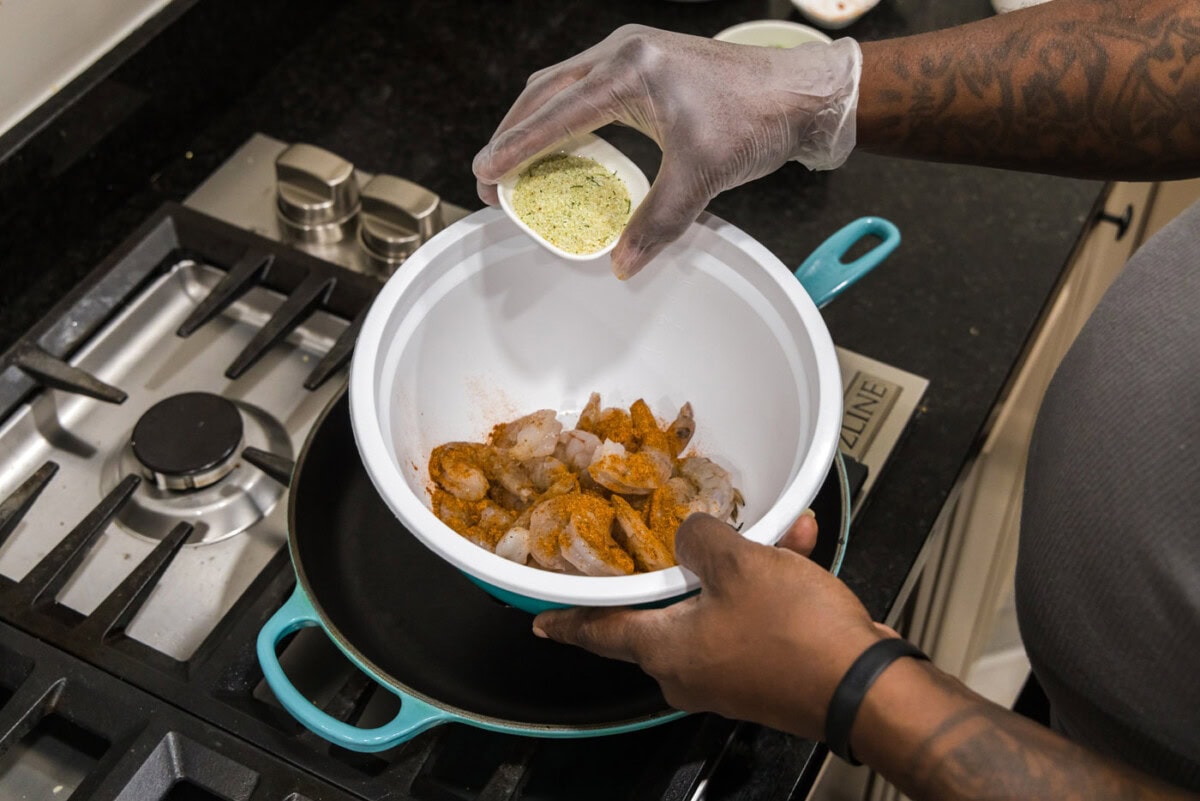 adding garlic salt to shrimp in a bowl
