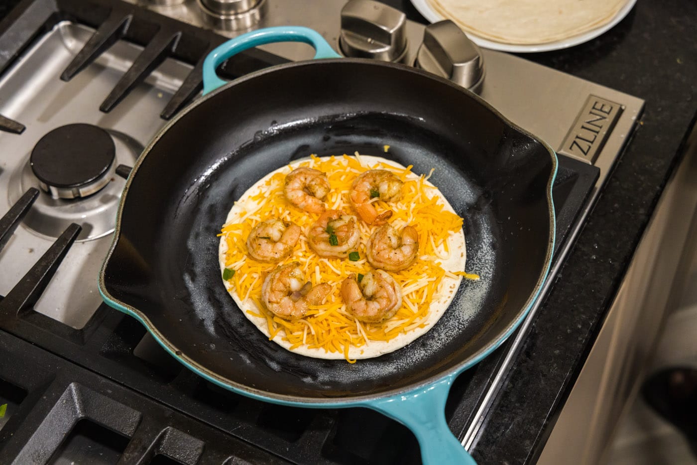 adding shrimp to tortilla with cheese