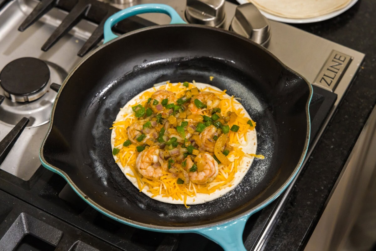shrimp, cheese, and sauteed veggies in a skillet