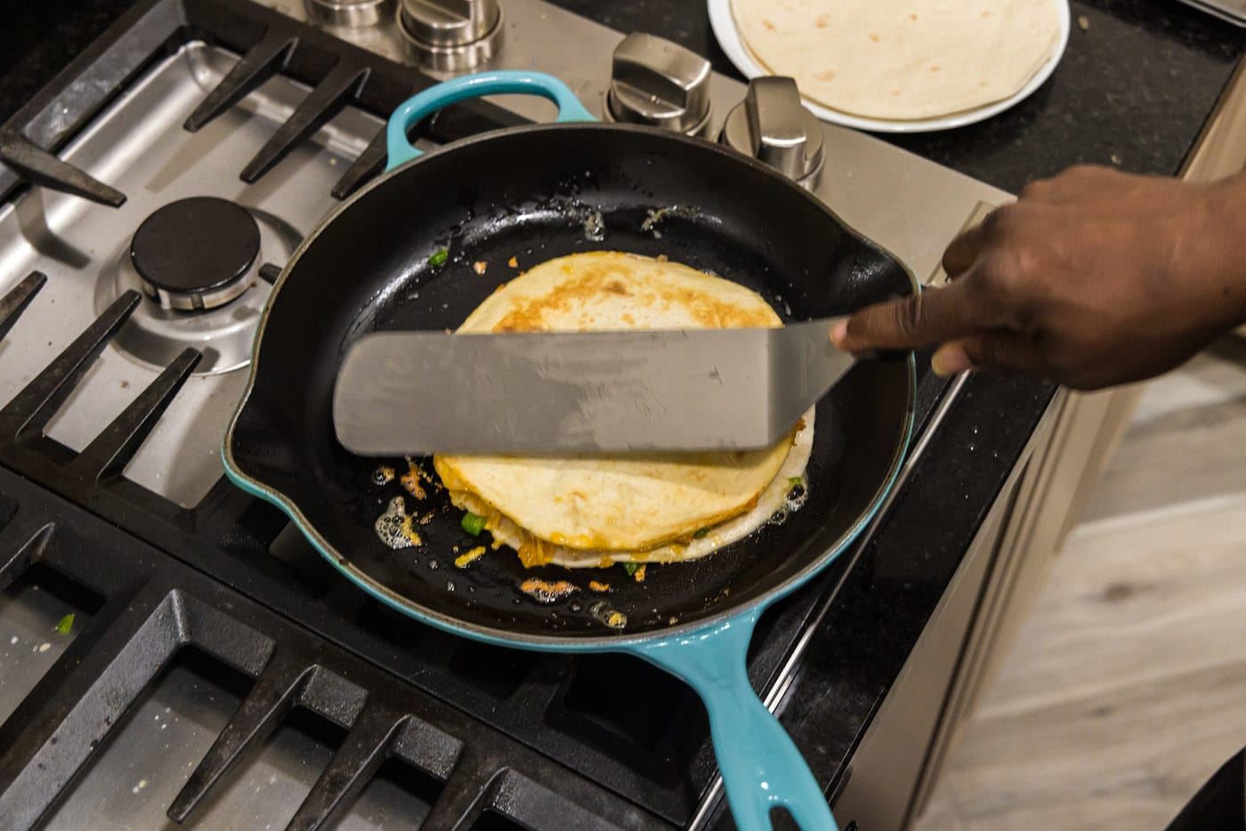 spatula pressing down on quesadilla in a skillet