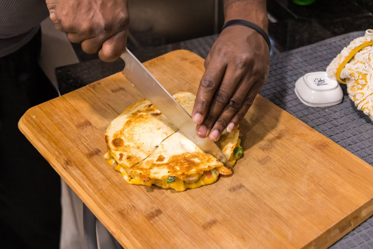 knife slicing shrimp quesadilla on a cutting board