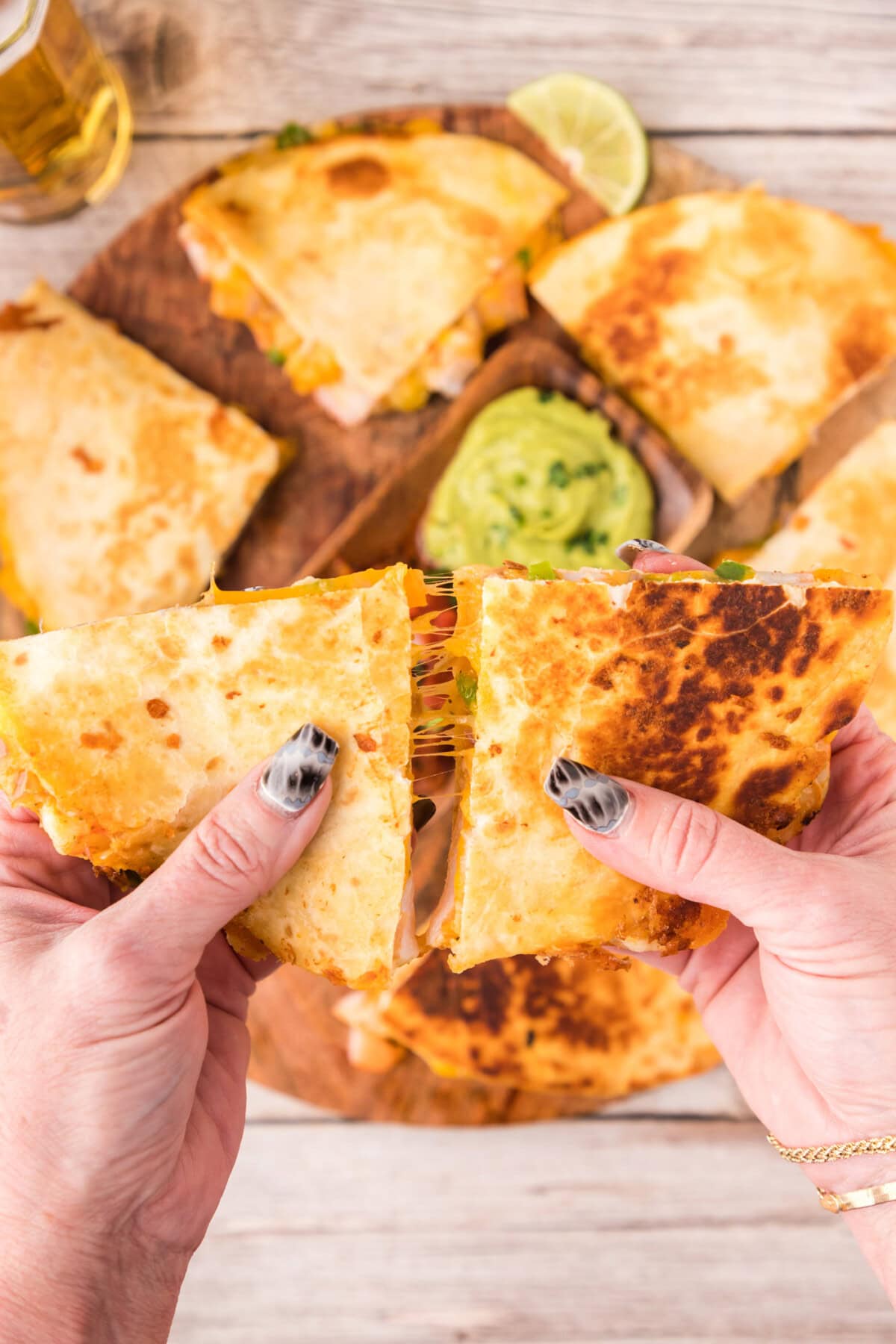 Hands pulling two Shrimp Quesadilla triangles apart