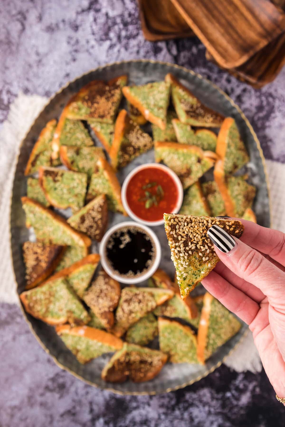 Shrimp Toast being held above a platter of Shrimp Toast