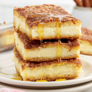 Stack of Sopapilla Cheesecake squares with honey drizzled on top