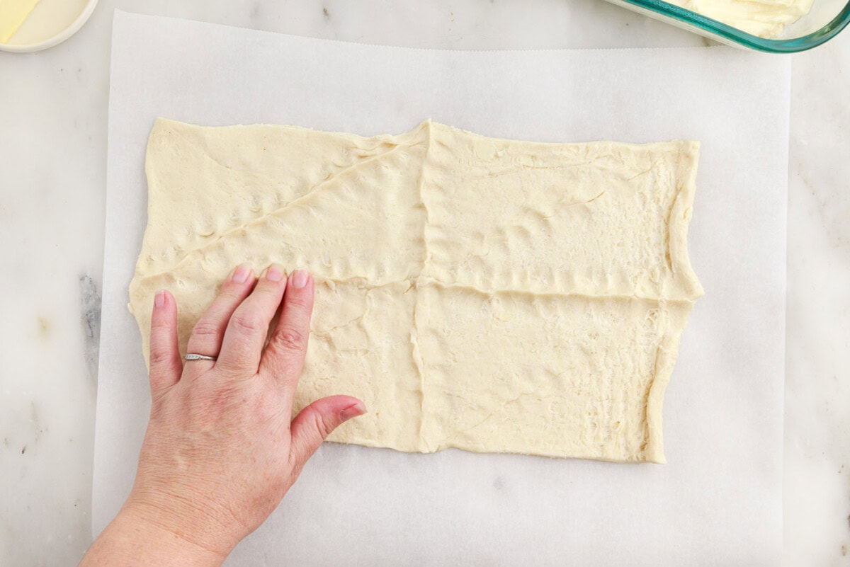 hand pressing the seams of crescent dough together