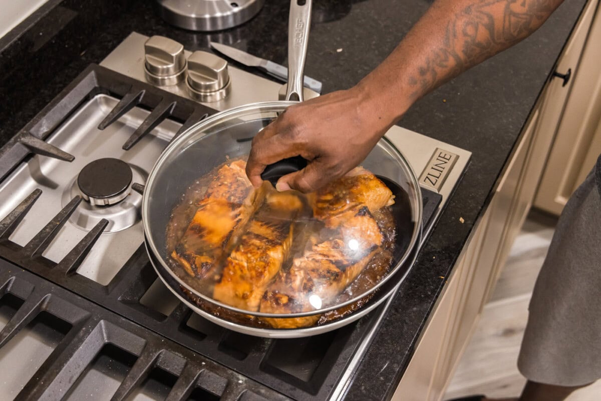 placing a lid on top of teriyaki salmon on the stovetop