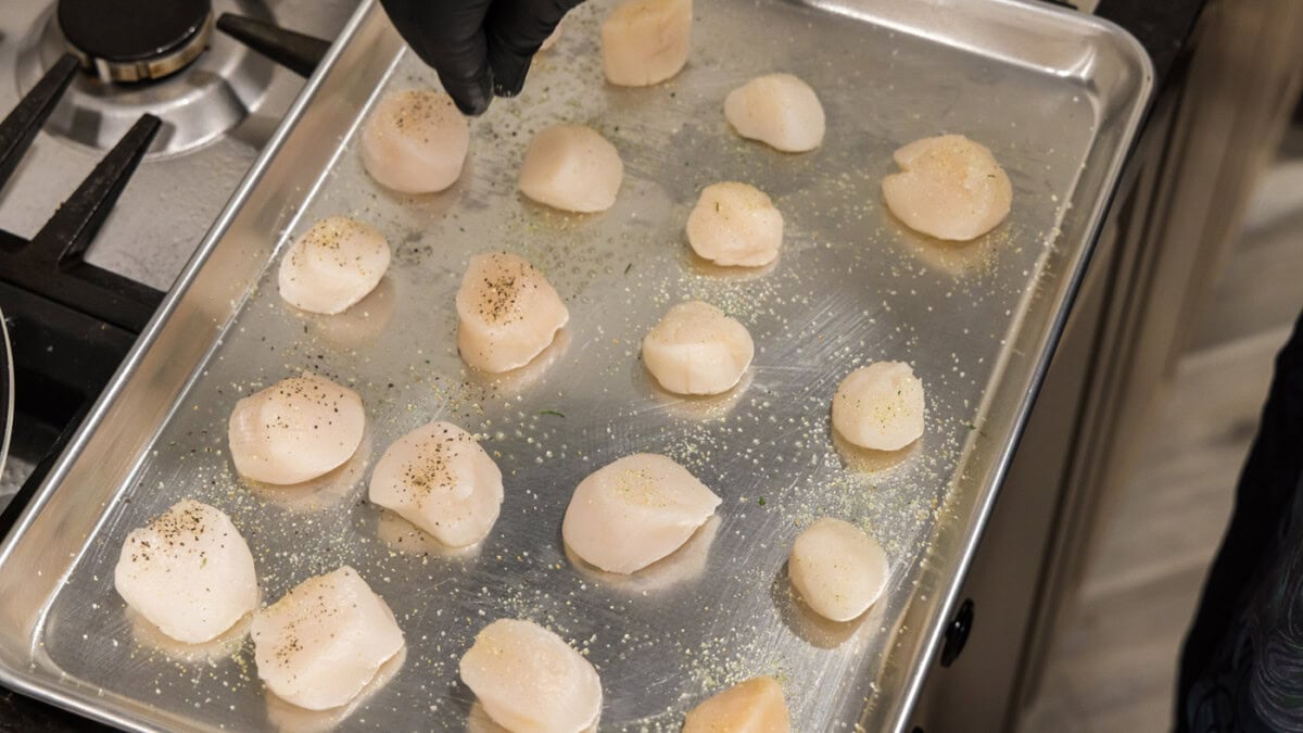 hand sprinkling garlic salt and pepper on scallops
