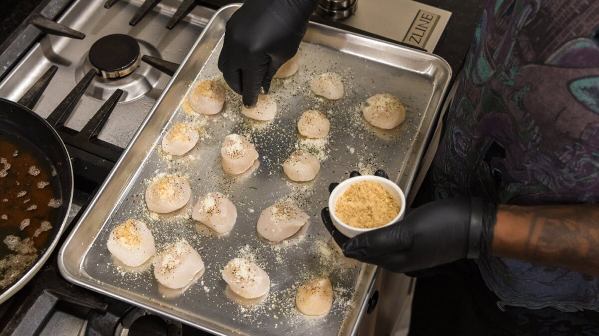sprinkling bread crumbs on top of scallops