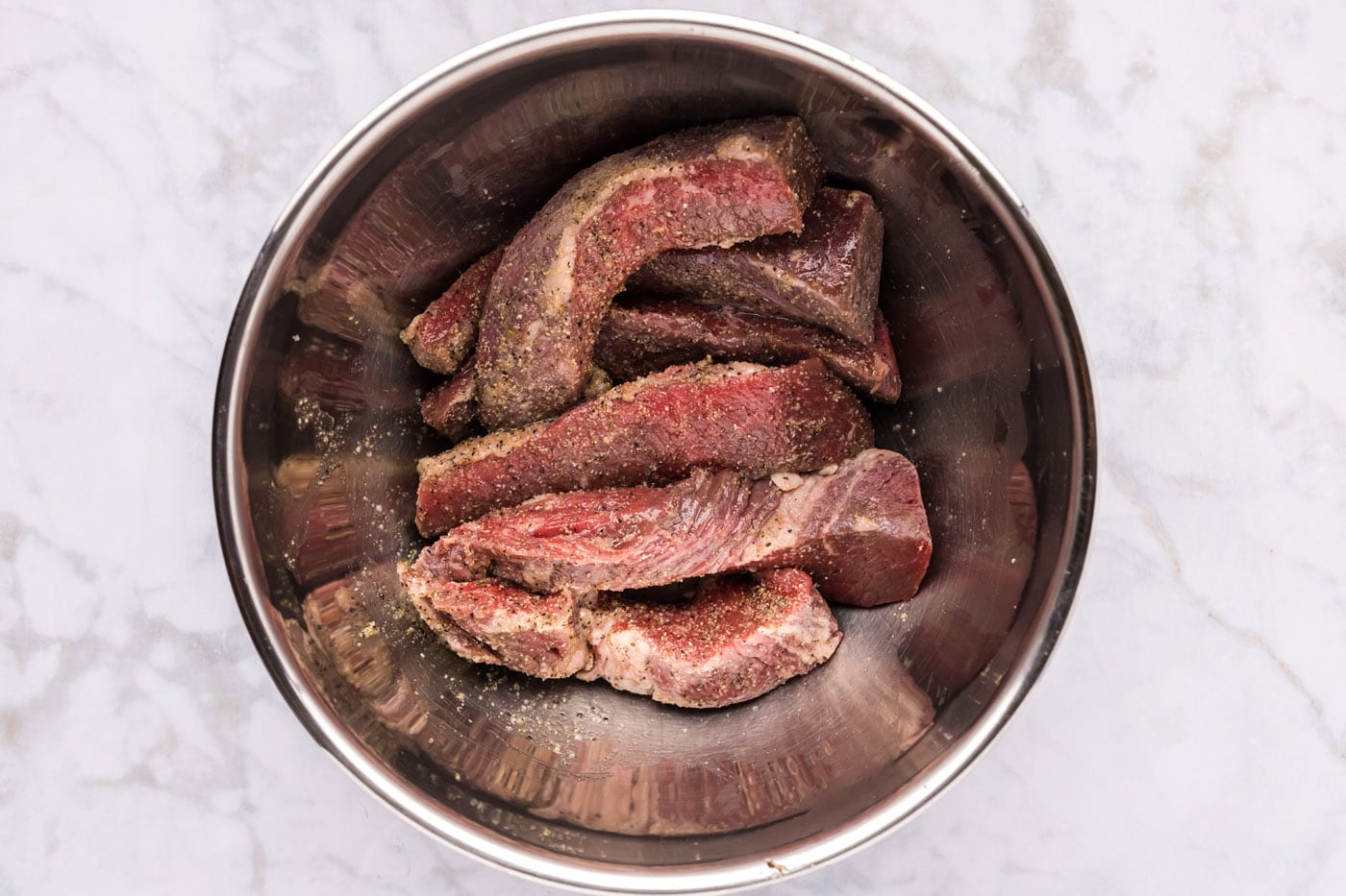 seasoned boneless beef short ribs in a mixing bowl