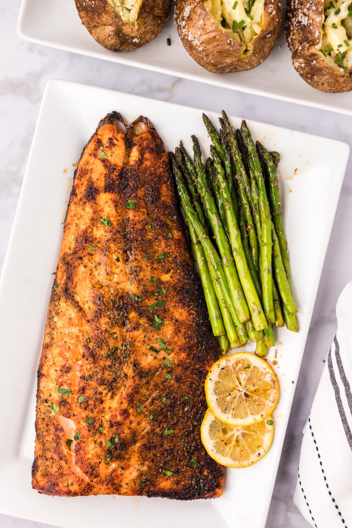 Broiled Salmon on a serving platter with sautéed asparagus and lemon slices