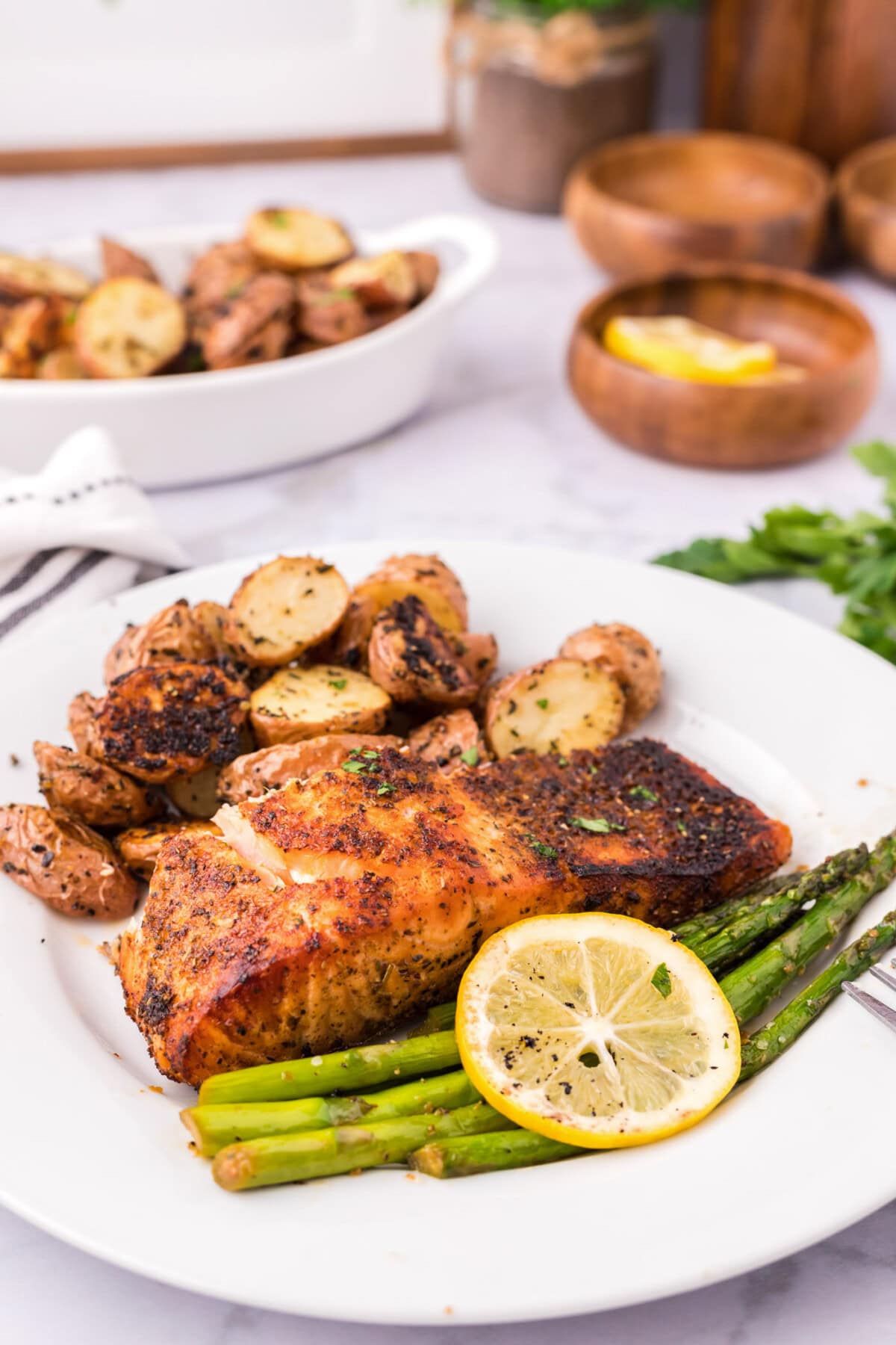 Slice of Broiled Salmon on a plate with sautéed asparagus and roasted red potatoes