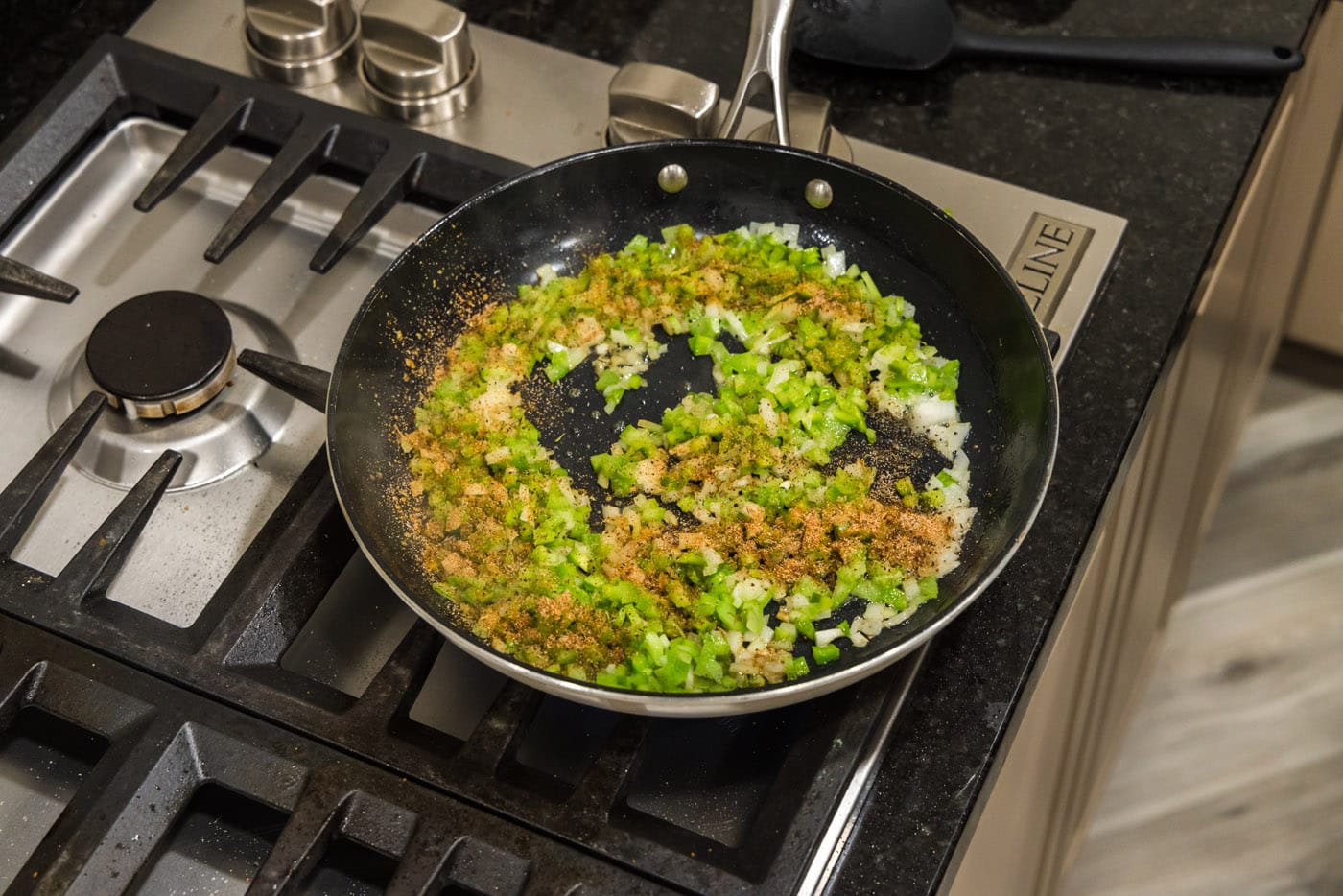 cajun seasoning on top of bell pepper, onion, and celery in a skillet