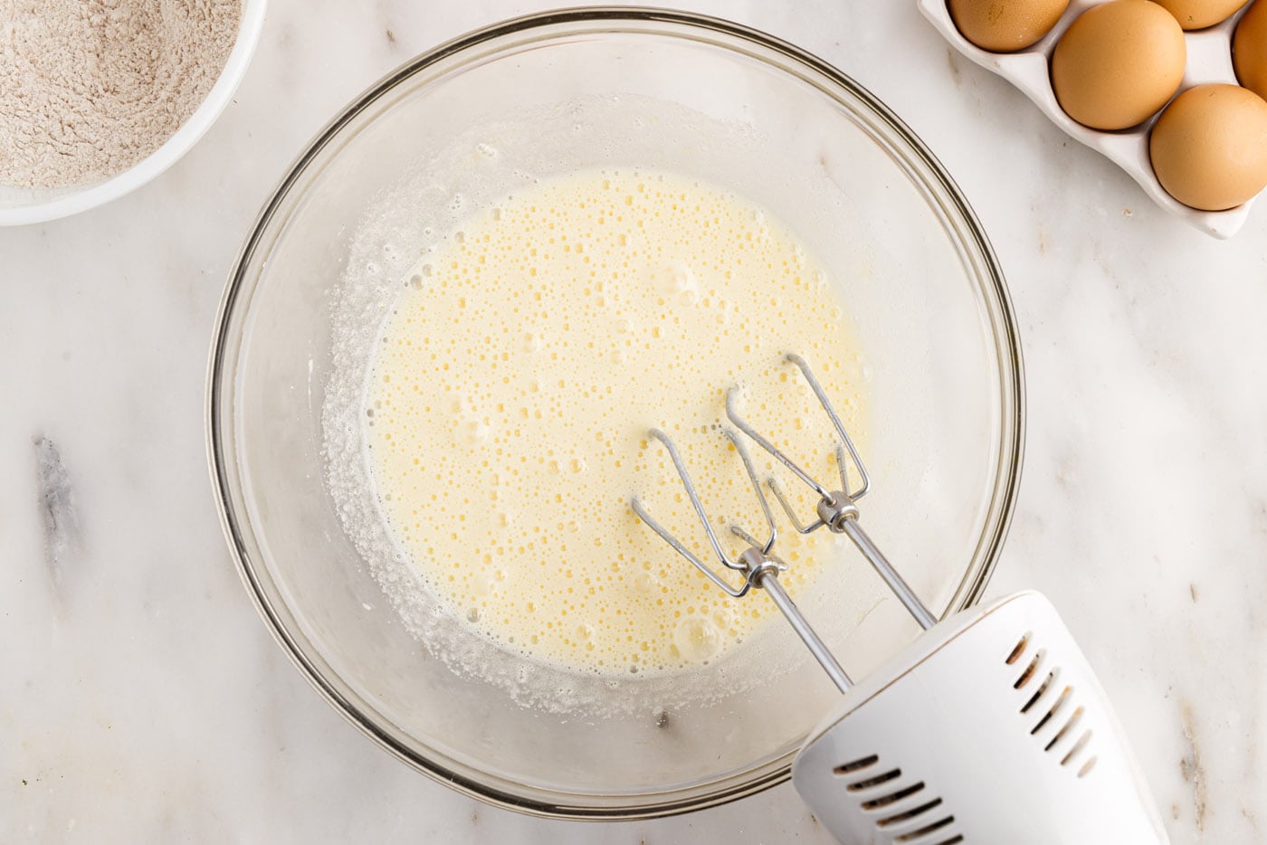 eggs and sugar mixed in a bowl with an electric mixer