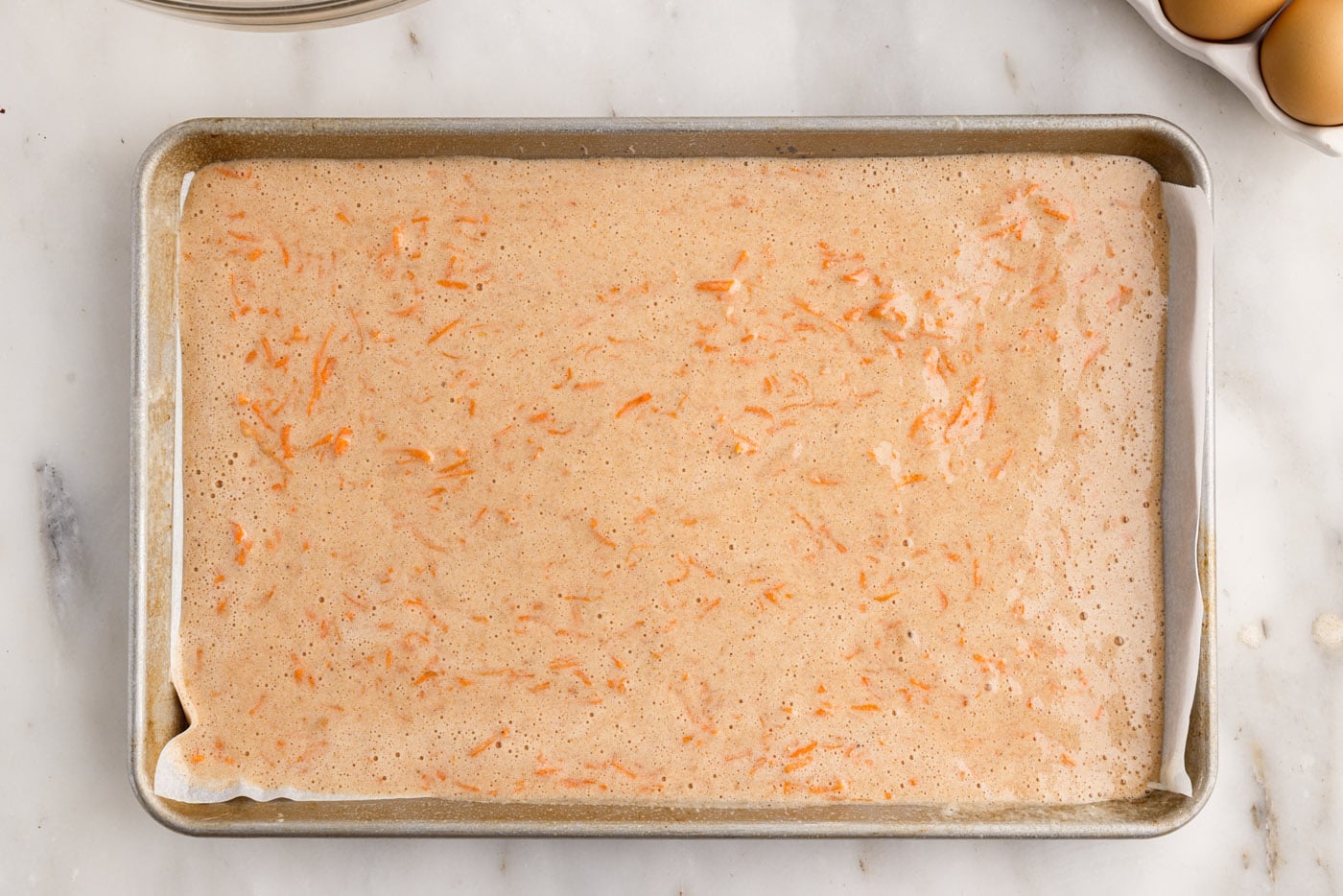 carrot cake roll batter in a jelly roll pan