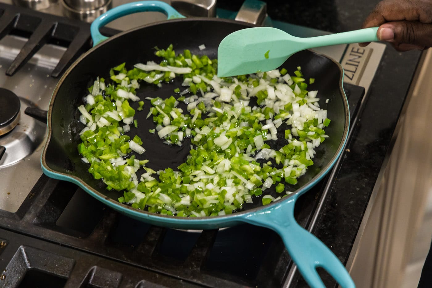 mixing green pepper and onion in a skillet