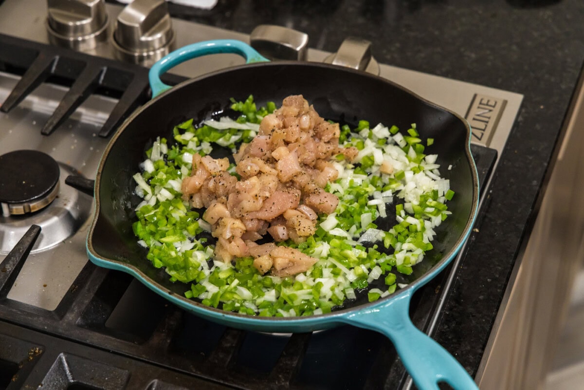 adding cubed chicken to skillet with veggies