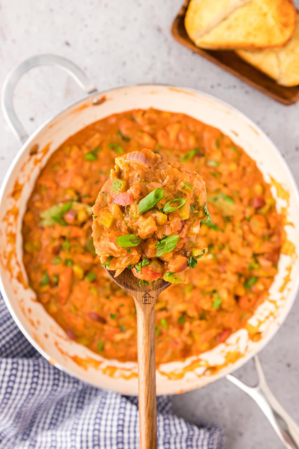 Spoonful of Crawfish Etoufee held above a skillet of Crawfish Etoufee