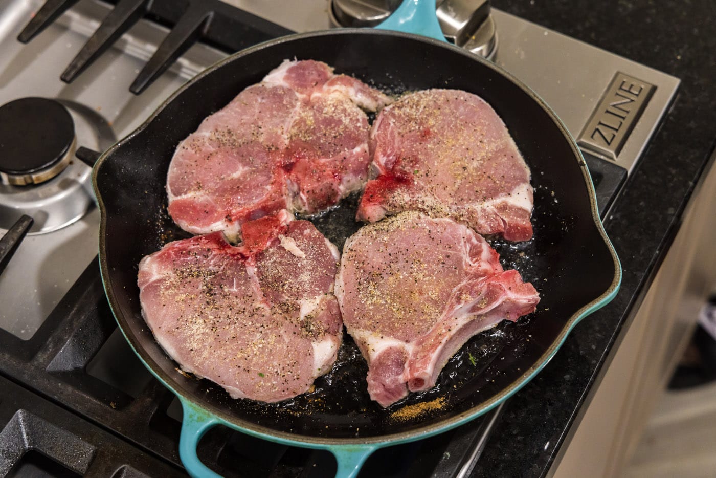 searing seasoned pork chops in a skillet