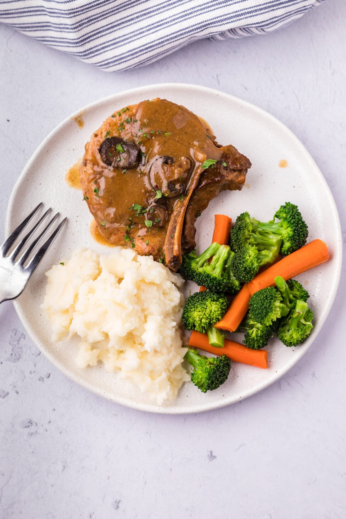 Crockpot Pork Chop served on a plate with mashed potatoes and mixed vegetables
