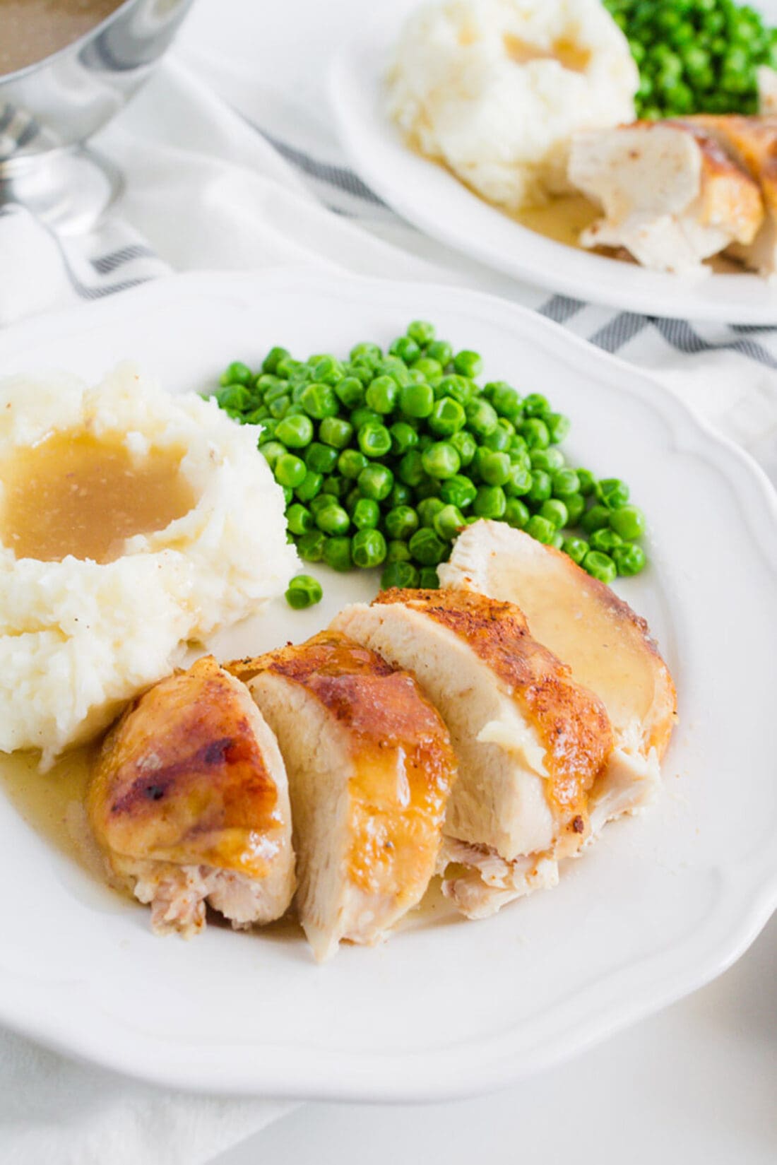 Crockpot Sticky Chicken on a plate with peas and mashed potatoes