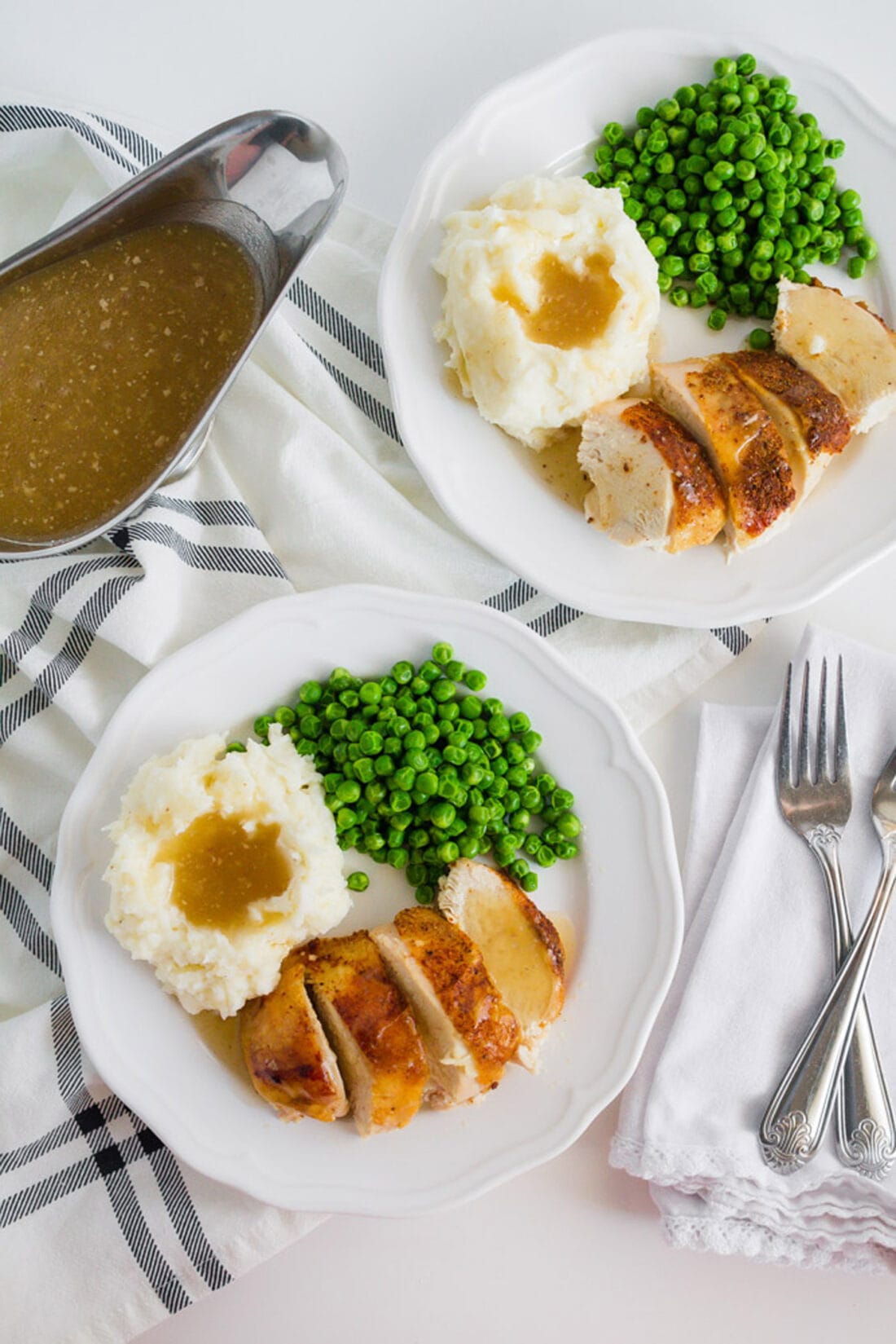 Two plates of Crockpot Sticky Chicken served with peas and mashed potatoes