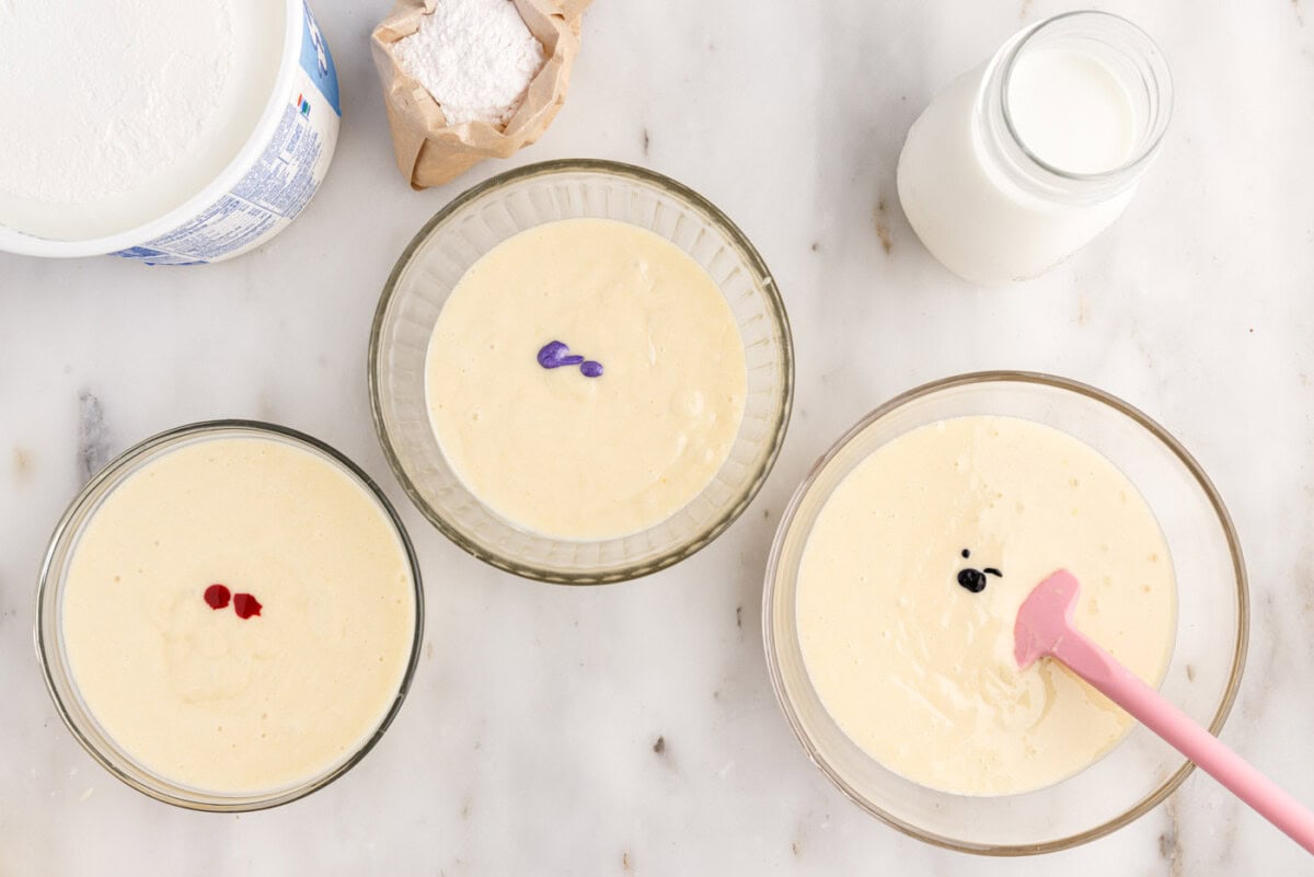 gel food coloring adding to bowls of cake batter