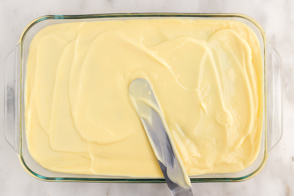 spreading vanilla pudding on top of cake