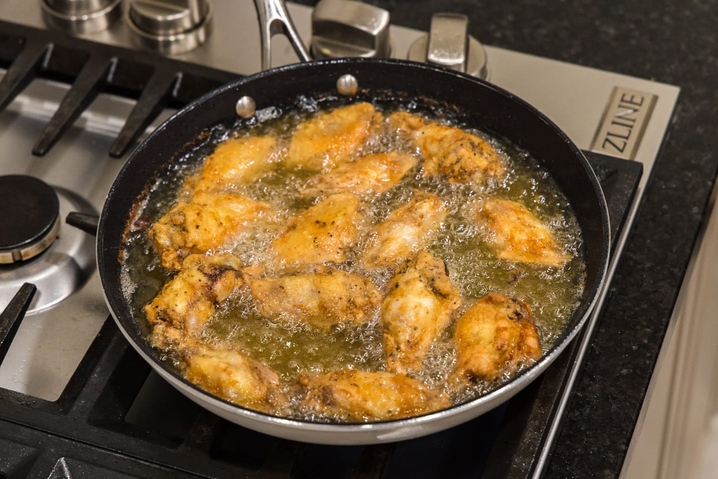 fried chicken wings in a skillet of oil