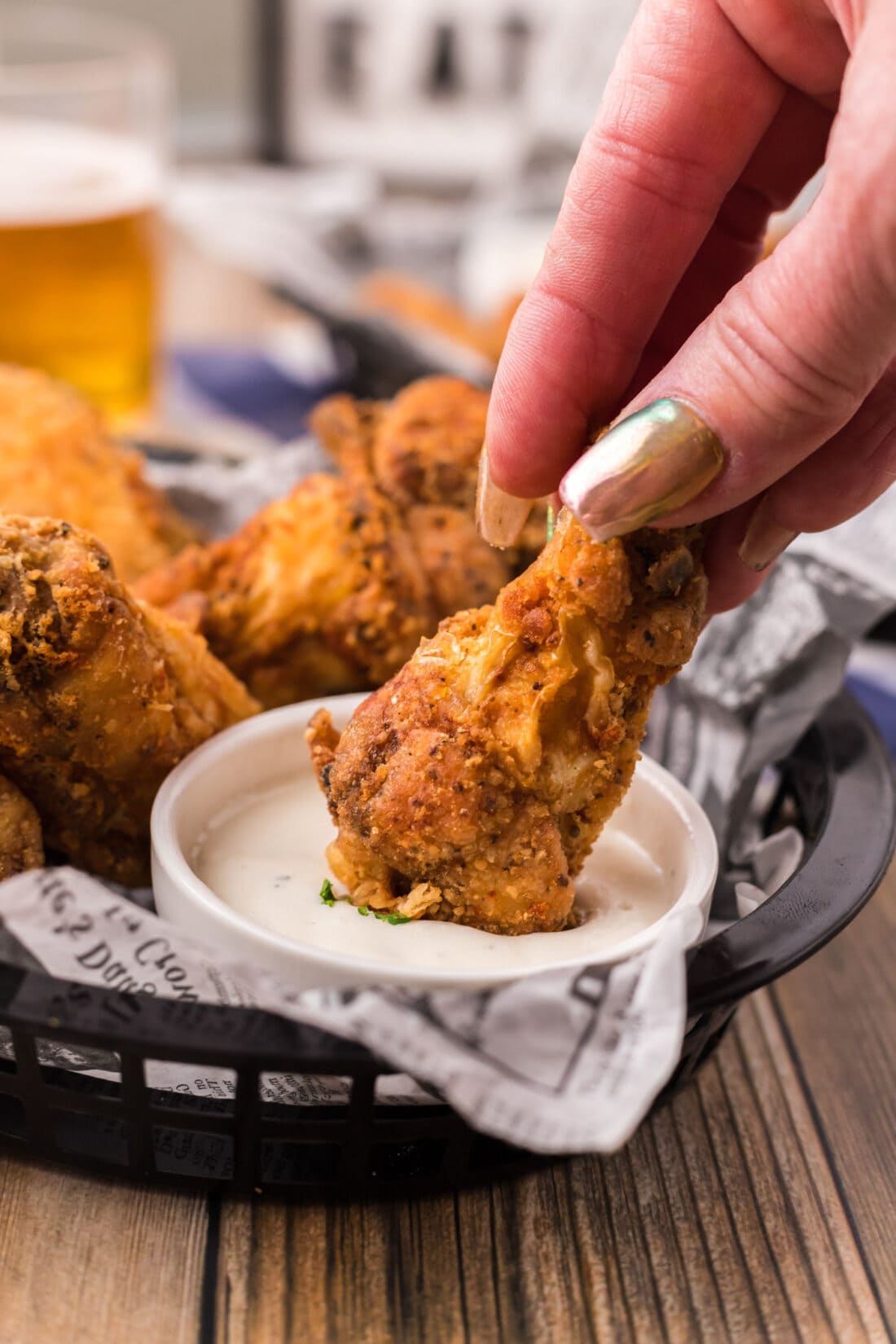 A Fried Chicken Wing being dipped into a bowl of ranch