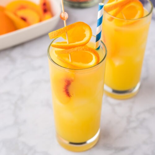 Fuzzy Navel with a straw and orange slices garnished on top