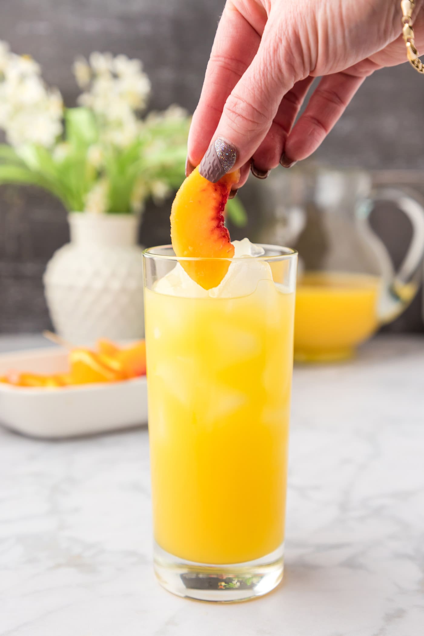adding frozen peach slices to fuzzy navel cocktail